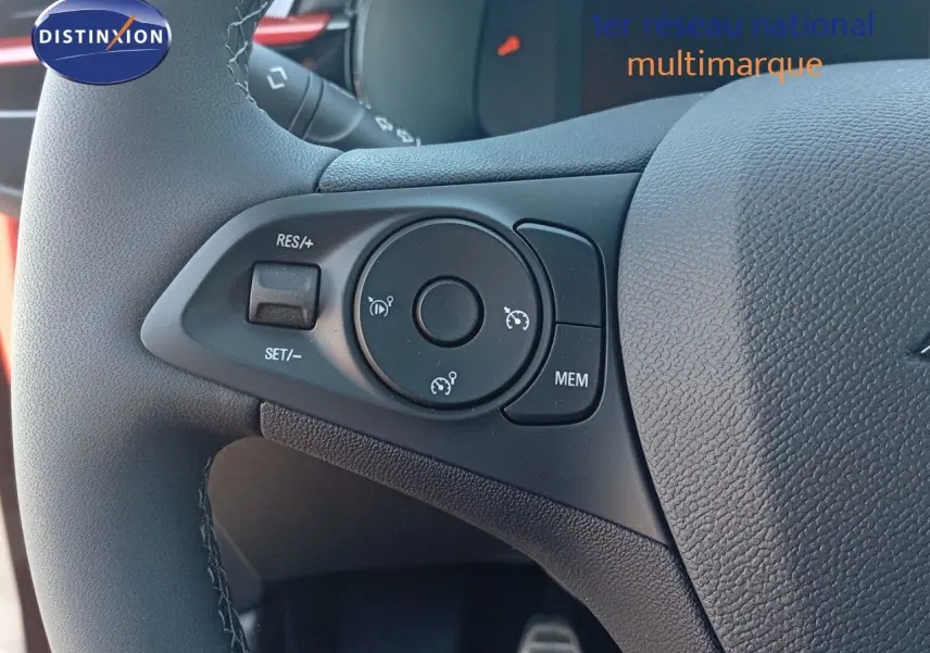 Gros plan sur les commandes de régulateur de vitesse au volant d'une Opel Corsa rouge Kardio métal avec toit noir.