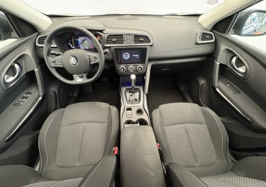 Vue intérieure avant du Renault Kadjar Intens 2019, tableau de bord noir avec écran tactile central et sièges tissu gris.