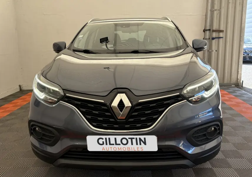 Vue avant d'un Renault Kadjar Intens gris foncé avec phares LED allumés dans un showroom.