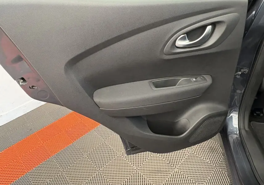 Porte arrière gauche ouverte du Renault Kadjar gris foncé, montrant la garniture intérieure noire avec poignée et commande de vitre.