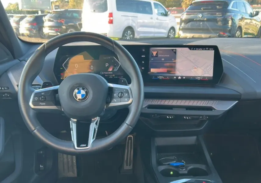 Vue intérieure du poste de conduite de la BMW Série 1 2025, avec volant sport et écran tactile central.
