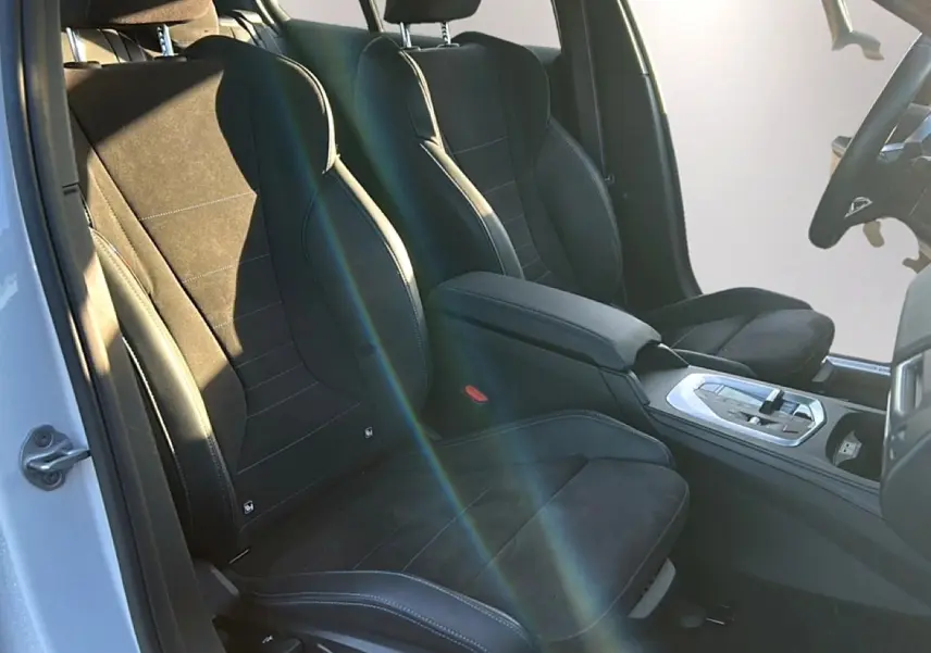 Vue intérieure côté conducteur de la BMW Série 1 2025, sièges sport en alcantara noir avec coutures bleues.