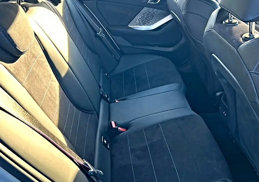 Vue intérieure des sièges arrière en tissu alcantara noir avec surpiqûres bleues d'une BMW Série 1 2025.