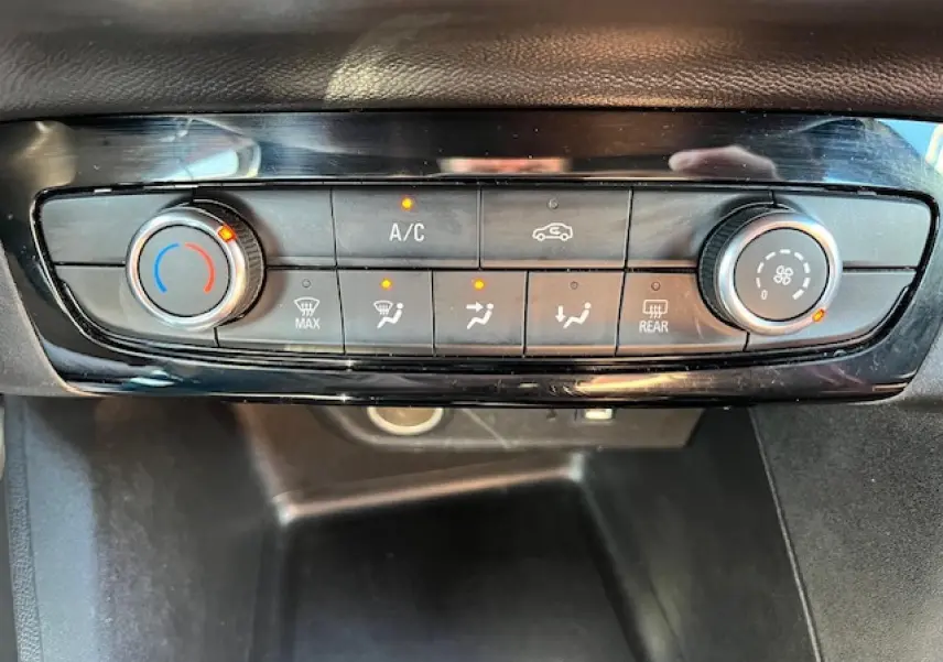 Gros plan sur la console de climatisation de l'Opel Corsa 1.2i Turbo 2021 avec commandes digitales et boutons rétroéclairés.