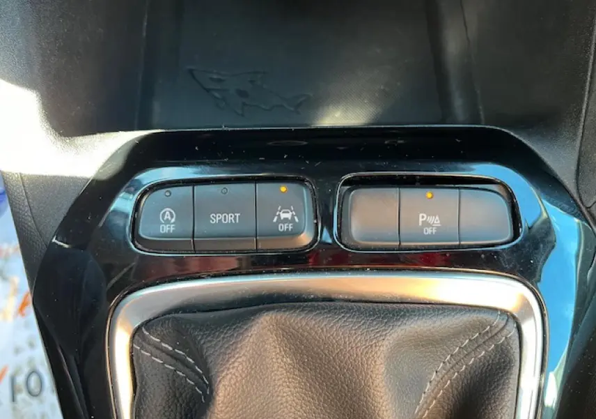 Gros plan sur la console centrale de l'Opel Corsa 2021, boutons de mode sport et aide au stationnement activés.