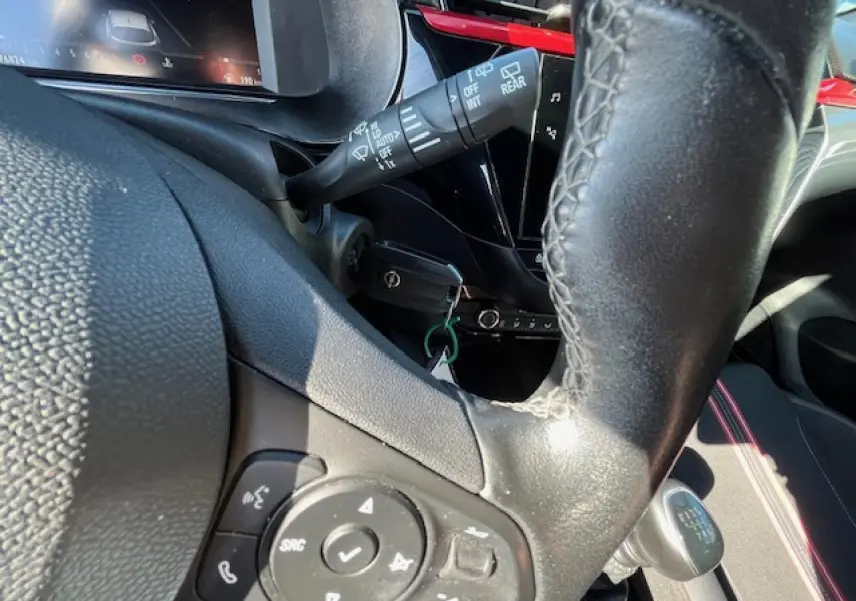 Gros plan sur le volant cuir multifonction et levier de vitesse manuel de l'Opel Corsa gris/noir, intérieur moderne et lumineux.