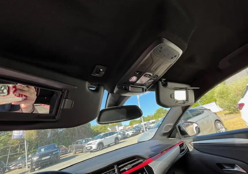 Intérieur de l'Opel Corsa 2021 gris/noir, vue du tableau de bord côté passager avec pare-soleil ouvert et rétroviseur central.