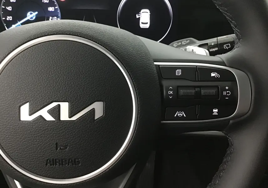 Gros plan sur le volant cuir noir du Kia Sportage 2025 avec commandes multifonctions et tableau de bord digital.