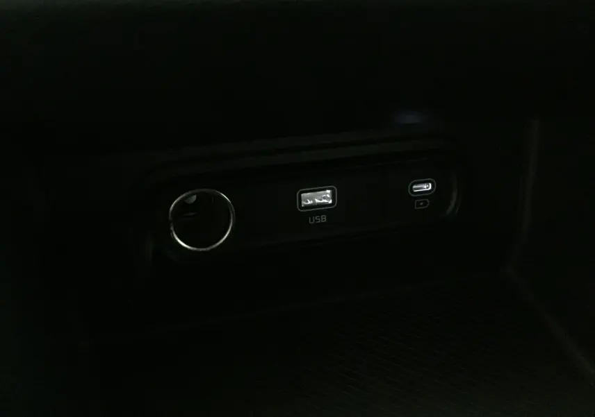 Prise USB et port allume-cigare en gros plan dans l'habitacle du Kia Sportage gris Sirius 2025.