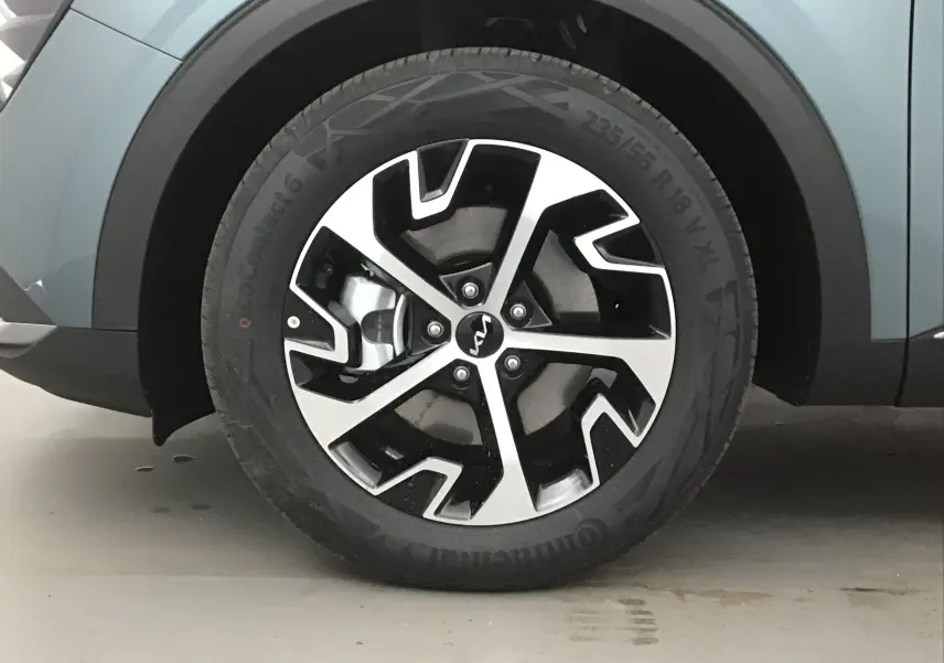 Gros plan sur la roue avant gauche du KIA SPORTAGE gris Sirius avec jante alliage noire et argentée au design moderne.