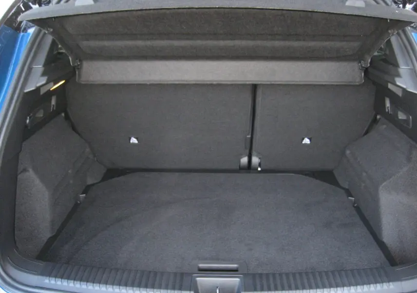 Coffre ouvert vu de l'arrière d'un Renault Austral bleu outremer avec intérieur de coffre noir et cache-bagages déployé.