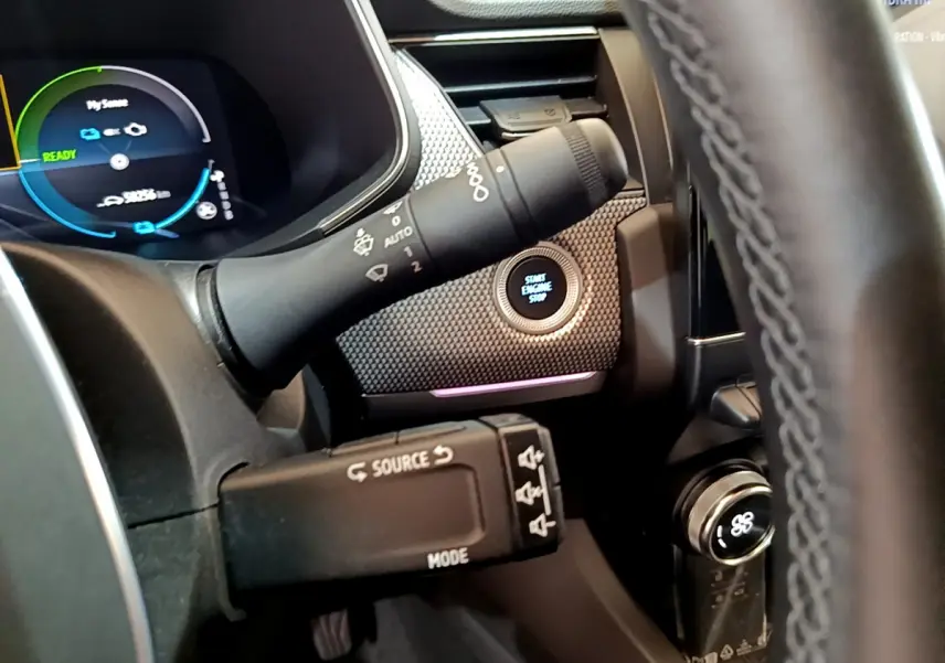 Gros plan intérieur sur le tableau de bord du Renault Arkana bleu, avec bouton démarrage et commandes au volant visibles.