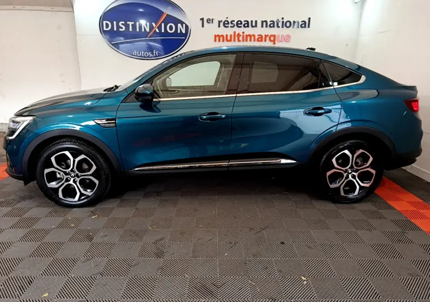Renault Arkana bleu en profil droit, soulignant ses jantes alliage distinctives et sa silhouette coupé SUV.