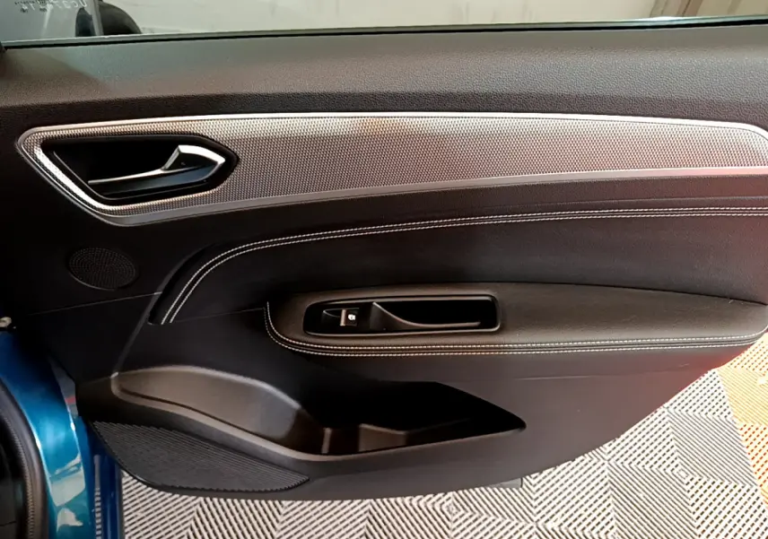 Vue intérieure du panneau de porte avant gauche bleu du Renault Arkana 2023 avec surpiqûres blanches et insert décoratif argenté.