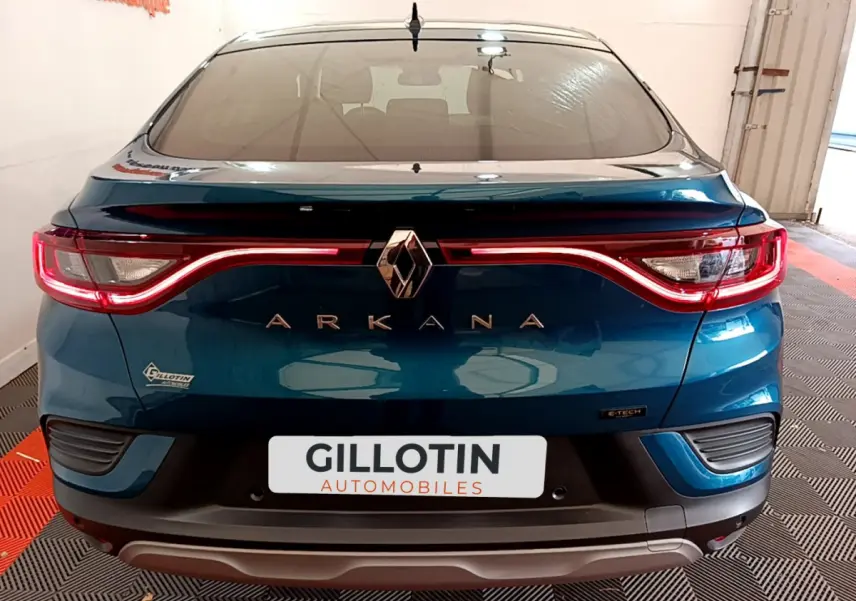 Vue arrière d'une Renault Arkana bleu électrique avec feux LED allumés dans un showroom.