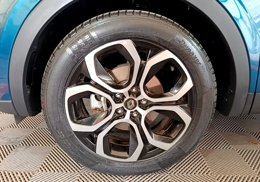 Gros plan sur la roue avant droite du Renault Arkana bleu, mettant en valeur la jante alliage noire et argentée au design moderne.