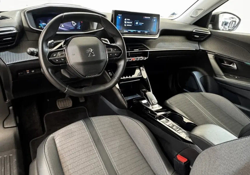 Intérieur avant droit du Peugeot 2008 gris foncé 2022, volant compact, écran tactile et sièges tissu gris.