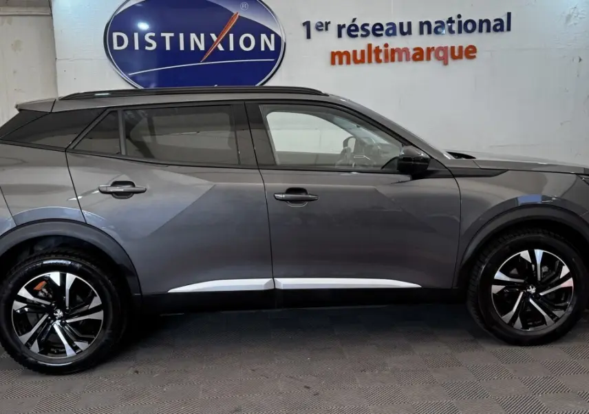 Profil droit d'un Peugeot 2008 gris foncé 2022 avec jantes alliage noires et toit noir contrasté.