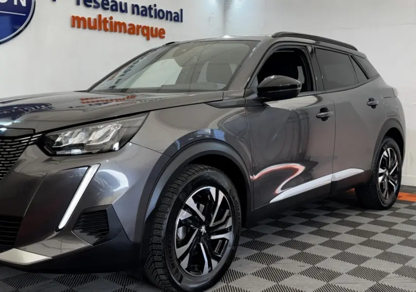 Peugeot 2008 gris foncé vue 3/4 avant droit, avec feux LED et jantes alliage noires distinctives.