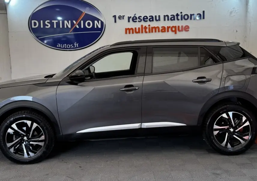 Profil côté gauche du Peugeot 2008 gris foncé 2022 avec jantes alliage bicolores et toit noir contrasté.