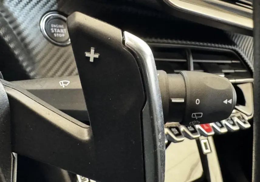 Gros plan sur la palette de changement de vitesse droite en plastique noir et chrome dans l’habitacle gris foncé du Peugeot 2008 2022.