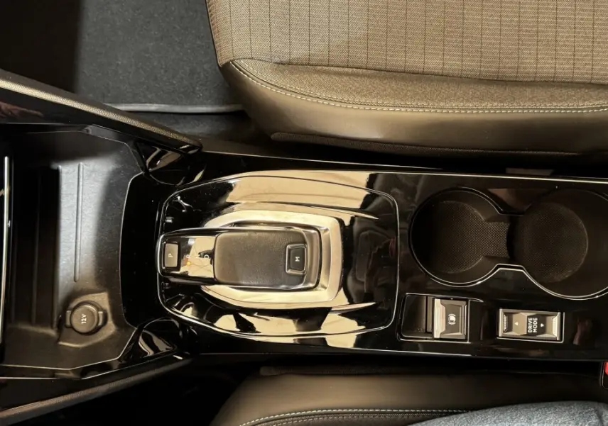 Vue plongeante sur la console centrale noire brillante du Peugeot 2008 gris foncé, avec levier de vitesse automatique et porte-gobelets.