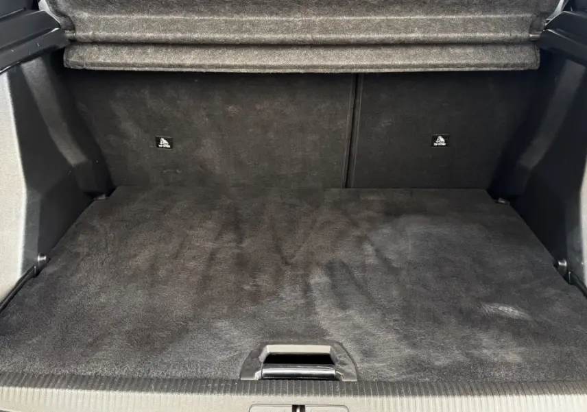 Coffre ouvert du Peugeot 2008 gris foncé, vue de face montrant l'espace de chargement vide et tapis noir.