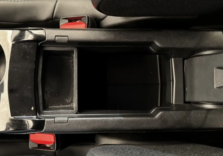 Vue plongeante sur la console centrale noire avec rangement ouvert et porte-gobelets du Peugeot 2008 gris foncé 2022.
