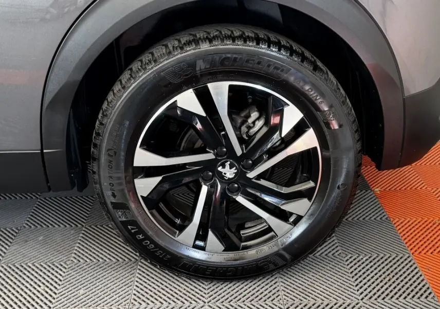 Gros plan sur la roue arrière droite du Peugeot 2008 gris foncé, mettant en valeur la jante alliage noire et argentée.