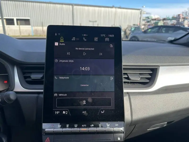 Vue intérieure du tableau de bord du Renault Captur 2025 avec écran tactile central et commandes climatisation visibles.