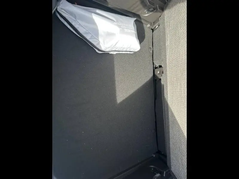 Vue du coffre arrière du Renault Captur 2025 blanc nacré/noir, avec tapis noir et sac de secours gris.
