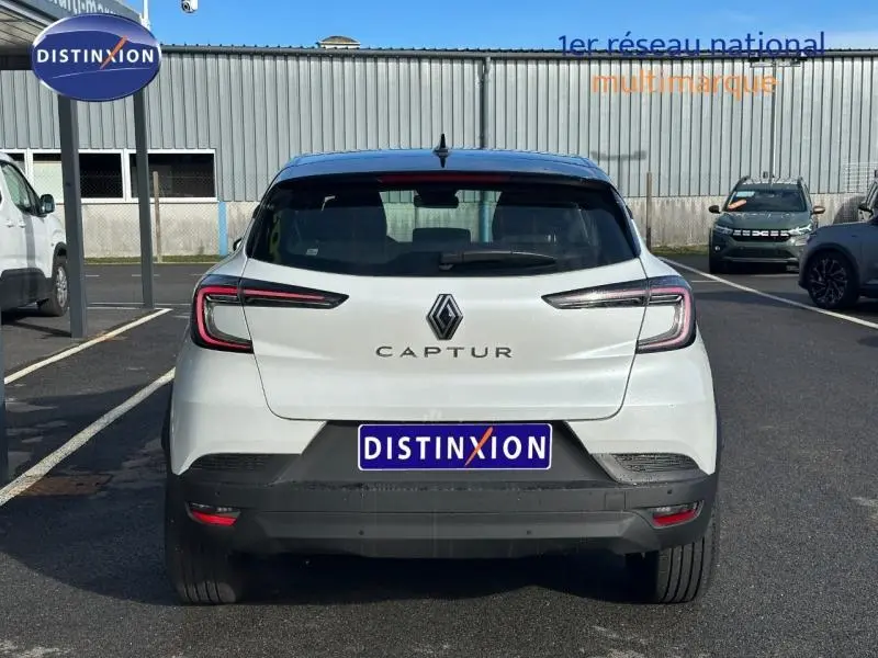 Vue arrière d'un Renault Captur blanc nacré avec toit noir, feux LED et logo central bien visibles.