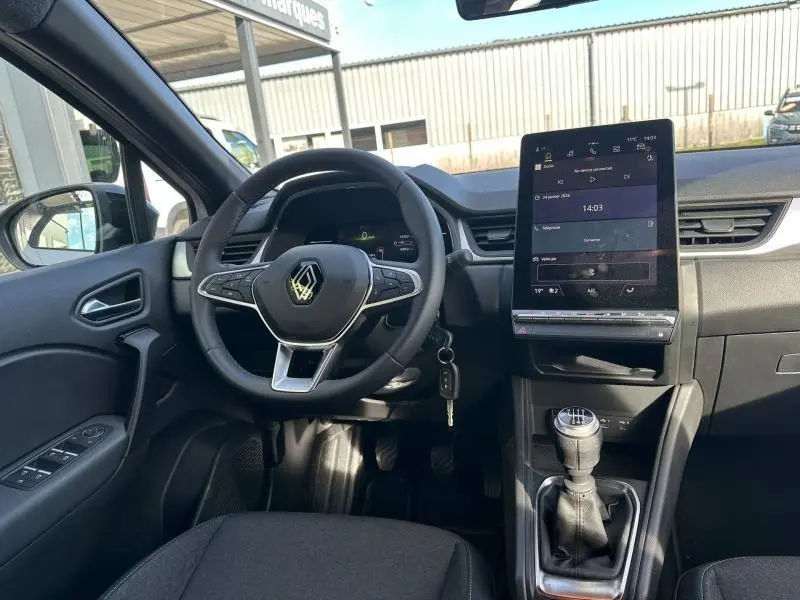 Vue intérieure avant du Renault Captur 2025 avec volant multifonction, écran tactile vertical et levier de vitesses manuel.