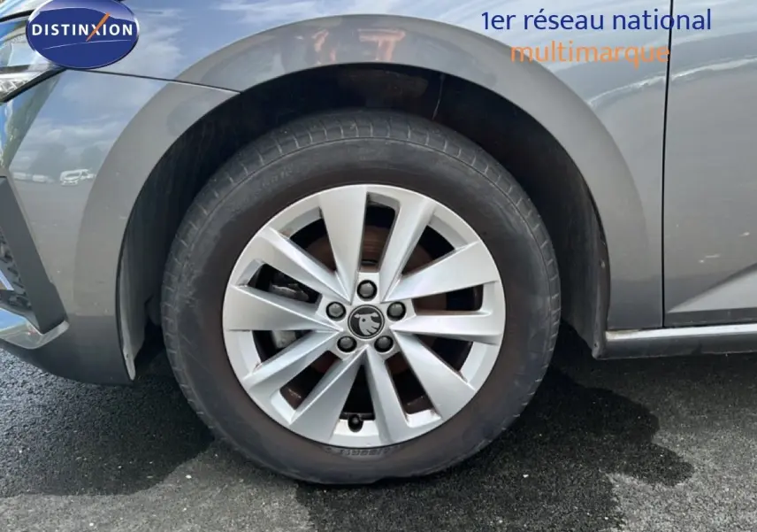 Gros plan sur la roue avant gauche d'une Skoda Scala gris magnétique métal avec jante alliage à dix branches.