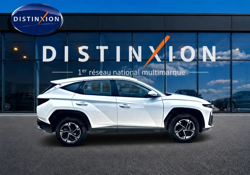 Profil droit d’un Hyundai Tucson blanc 2026 hybride, avec jantes alliage noires et toit noir contrasté.
