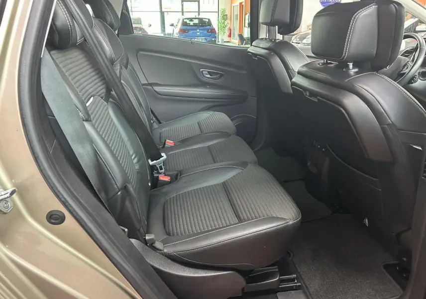 Vue côté gauche arrière du Renault Scénic Grand IV marron clair, mettant en valeur les sièges arrière en similicuir noir avec surpiqûres blanches.