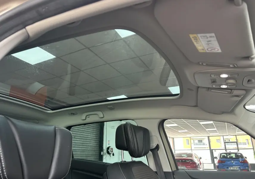 Vue intérieure du toit panoramique en verre du Renault Scenic Grand IV marron clair, avec sièges avant en similicuir noir.