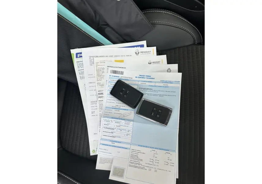Vue plongeante sur siège avant noir avec documents Renault et deux clés de voiture posées dessus.