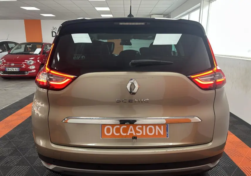 Vue arrière d'un Renault Scénic Grand IV marron clair avec feux LED allumés dans un showroom.