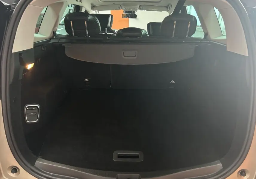 Coffre ouvert vu de l'arrière d'un Renault Scenic Grand IV marron clair avec cache-bagages et sièges arrière visibles.