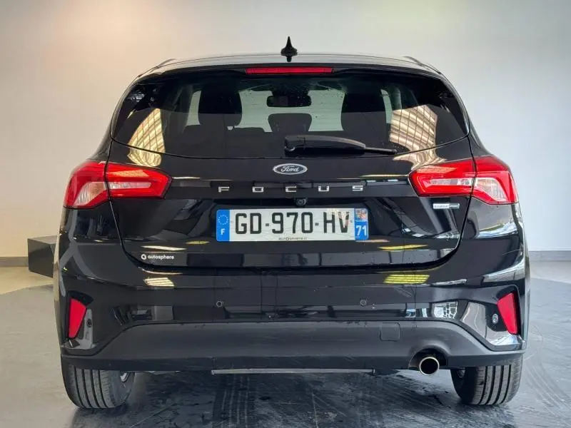 Vue arrière d'une Ford Focus noire Agate métallisé avec feux rouges et plaque d'immatriculation française visible.