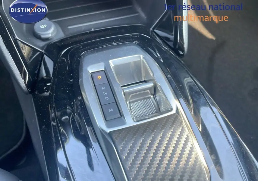 Gros plan sur la console centrale du Peugeot 2008 Hybrid 136ch avec levier de vitesses automatique et finition carbone.