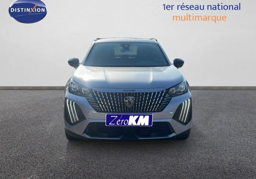 Vue frontale d'un Peugeot 2008 gris Artense métal avec feux LED verticaux allumés sur un sol bitumé.