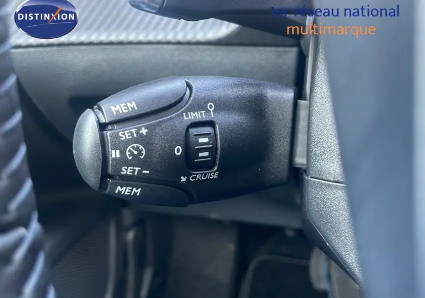 Gros plan sur la commande de régulateur de vitesse du Peugeot 2008 Hybrid gris Artense, côté gauche du volant.