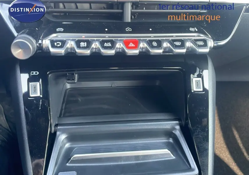 Gros plan sur la console centrale noire brillante du Peugeot 2008 Hybrid 136ch Allure, avec rangements et commandes.