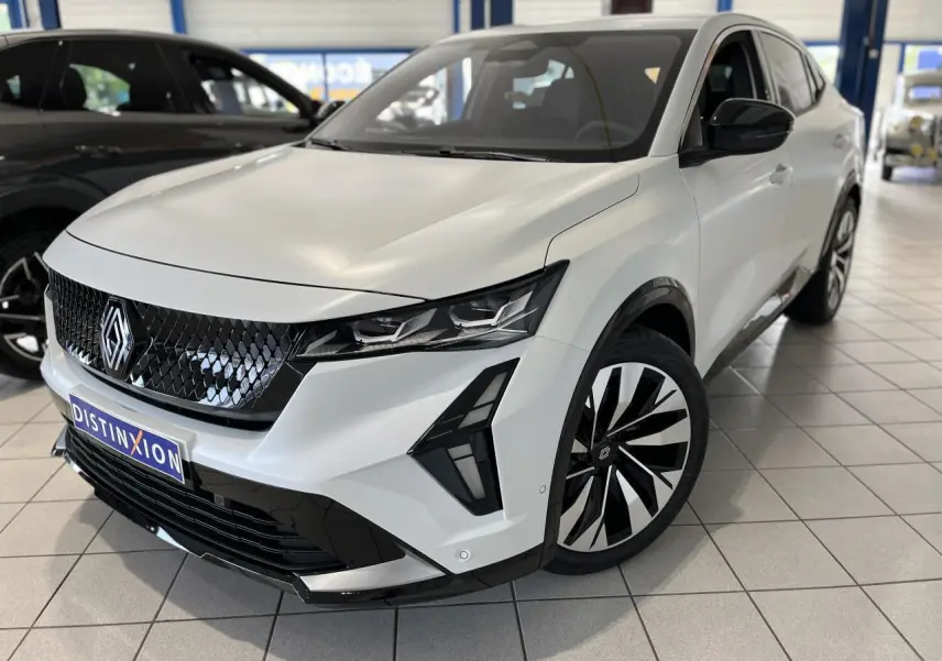 Renault Rafale blanc en 3/4 avant droit, avec calandre noire brillante et jantes alliage bicolores.