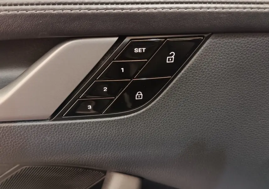 Gros plan sur les commandes de mémoire des sièges et verrouillage sur la porte intérieure côté conducteur, finition cuir noir.