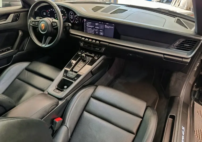 Vue intérieure côté conducteur de la Porsche 911 Carrera 4S Coupé 2019 avec tableau de bord numérique et sellerie cuir noire.