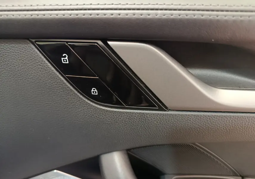 Détail des boutons de verrouillage sur la porte intérieure côté conducteur d’une Porsche 911 Carrera 4S Coupé gris foncé.