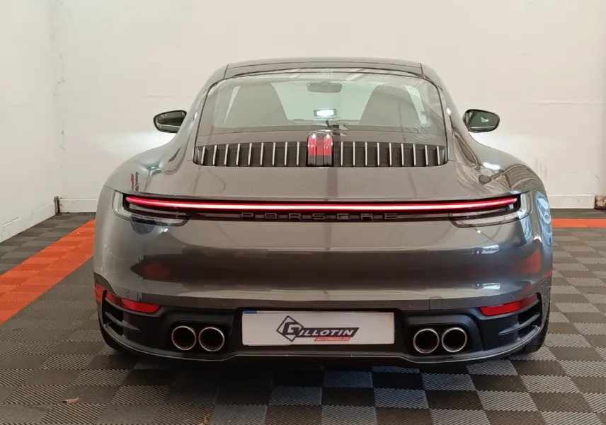 Vue arrière d'une Porsche 911 Carrera 4S Coupé gris foncé avec feux LED continus et quadruple sortie d'échappement.